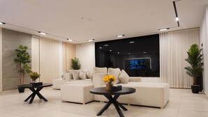 A modern living room with a sectional sofa, two side tables, and a flat-screen TV. - Tura Residence Sulemania (Riyadh)