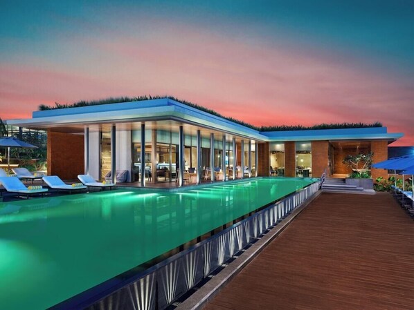 A modern hotel with a pool, lounge chairs, and a wooden deck. - Taj Puri Resort and Spa, Odisha (Brahmagiri)