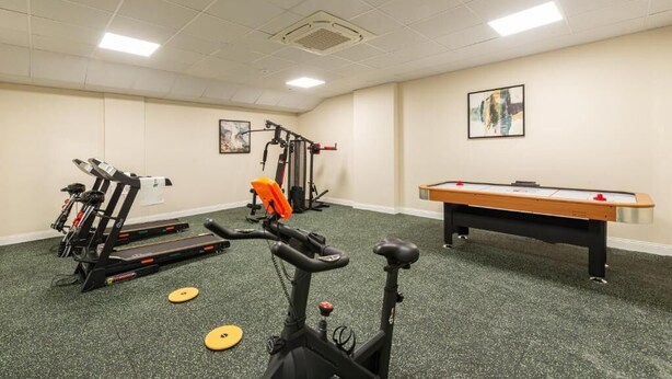 Ein Fitnessraum mit Trainingsgeräten, einem Billardtisch und Kunstwerken an den Wänden.