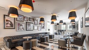 A modern lounge area with a black and white checkered floor, a black sofa, and multiple round tables.