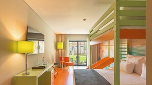 Habitación de hotel con literas, un escritorio con lámpara, una silla y vistas al exterior.