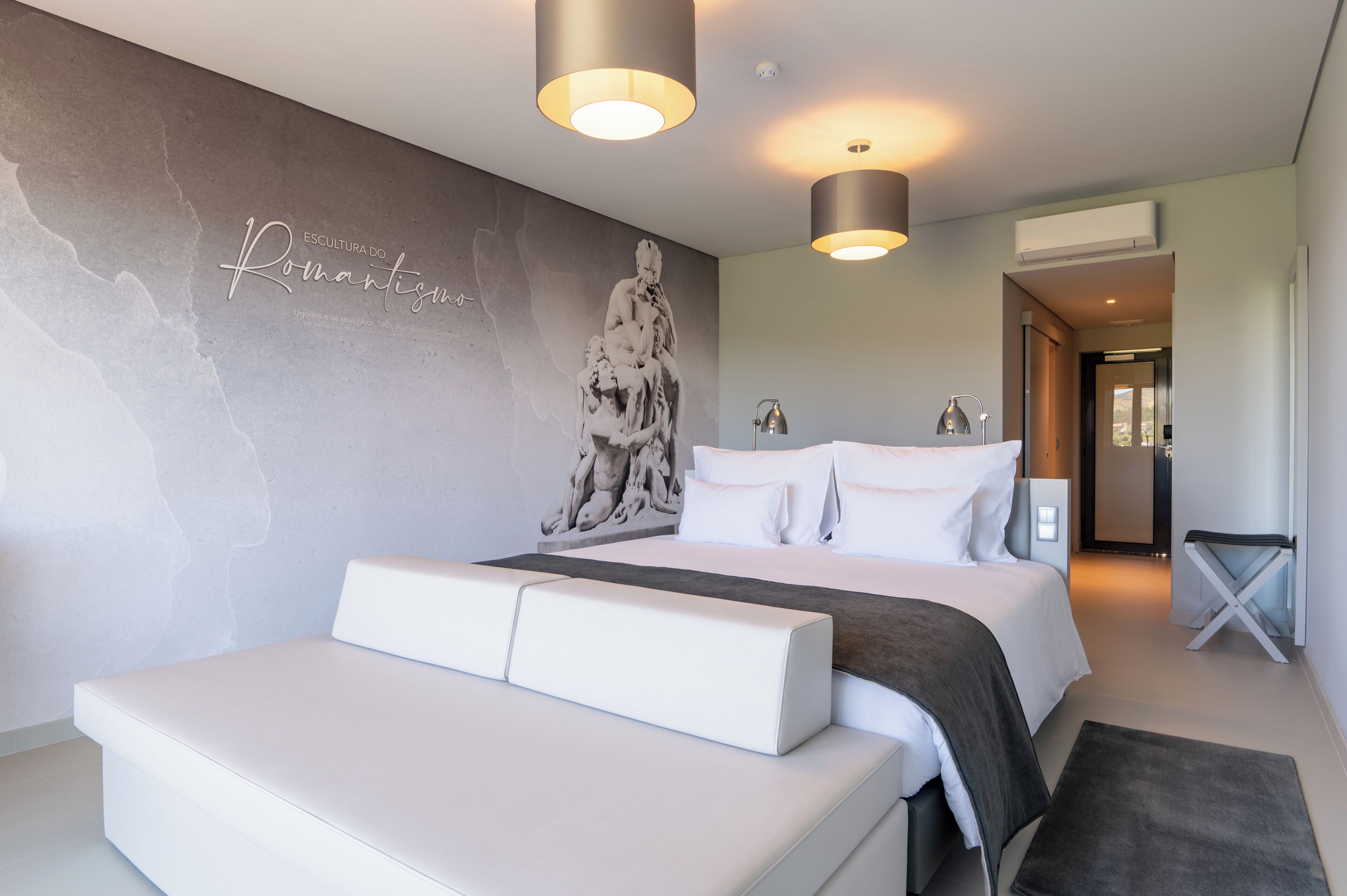 Una camera da letto moderna con un letto grande, una scultura a parete e due lampade a sospensione.