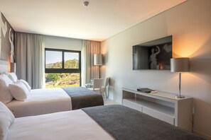 A hotel room with two beds, a desk, a chair, a TV, and a large window offering a view of the outdoors. - Vila Gale Collection Ponte de Lima Vineyards (Ponte de Lima)