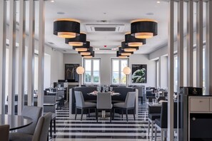 A modern dining area with a central round table, black and white striped flooring, and pendant lighting. - Vila Gale Collection Ponte de Lima Vineyards (Ponte de Lima)