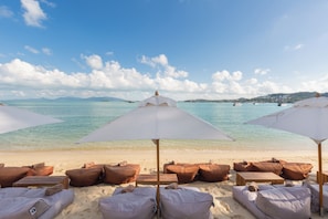 A beach with sun loungers and umbrellas, a clear sky, and calm waters. - Chi The Residence (Koh Samui)