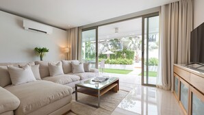 A modern living room with a beige sofa, a glass coffee table, and a TV on a wooden console.