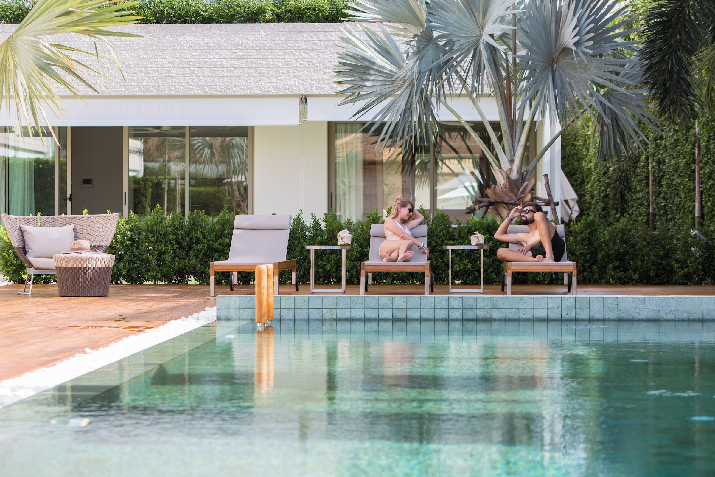 A poolside area with lounge chairs, a small table, and a bench.