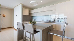 A modern kitchen with a central island, bar stools, a built-in oven, and a large window.