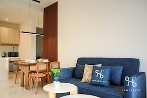 Un salon moderne avec un canapé bleu, une table à manger en bois et des chaises. On y trouve une petite table blanche sur laquelle est posée une plante.