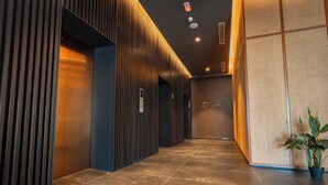 A corridor with a modern design, featuring a wooden slat wall on one side and a textured wall on the other. - The Sigar Hotel (Kota Kinabalu)