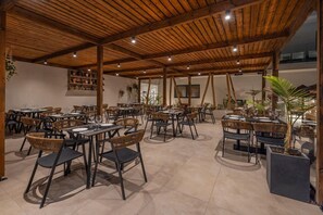 An outdoor dining area with multiple tables and chairs, wooden ceiling beams, and potted plants. - Cabana White Boutique Hotel & Suites (Kos)