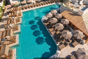Vista aérea de un resort con piscina, tumbonas y sombrillas.