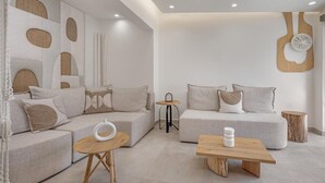 A modern living room with two sofas, a coffee table, and a wall with abstract designs. - Cabana White Boutique Hotel & Suites (Kos)