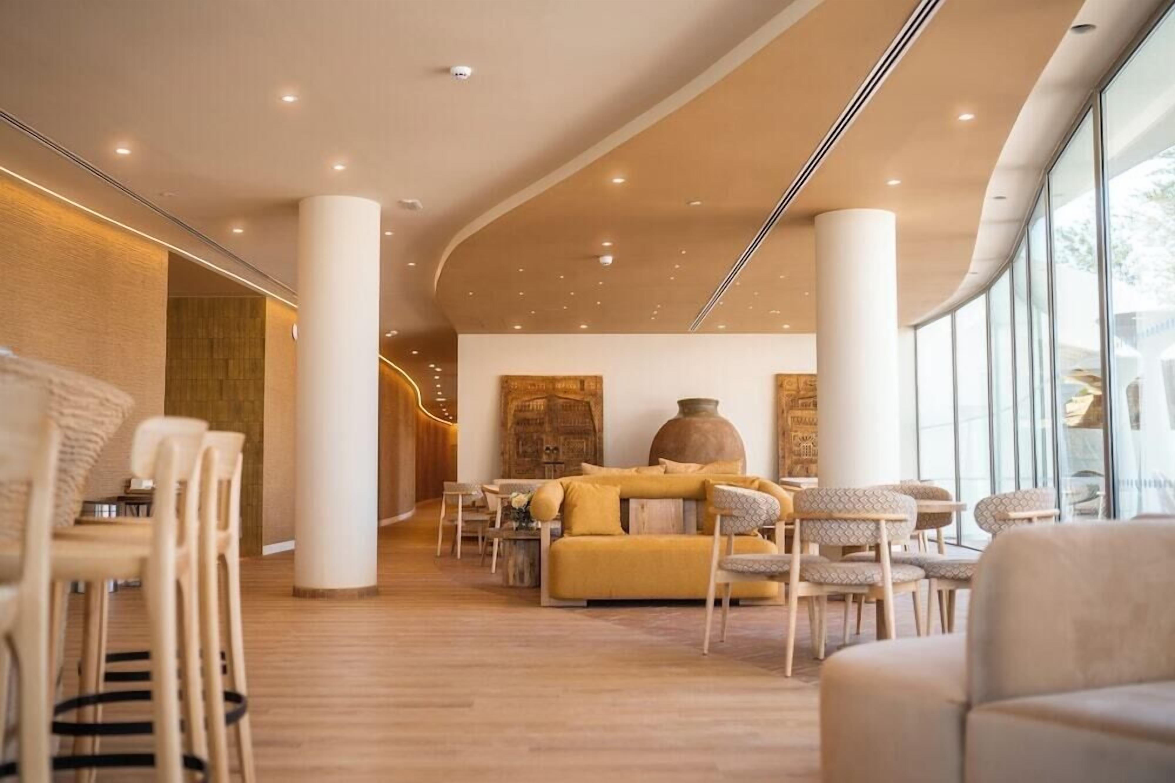 A modern interior with a central seating area, wooden flooring, and large windows.
