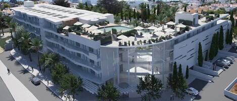 A modern hotel with a rooftop pool, surrounded by palm trees and a clear view of the sea.
