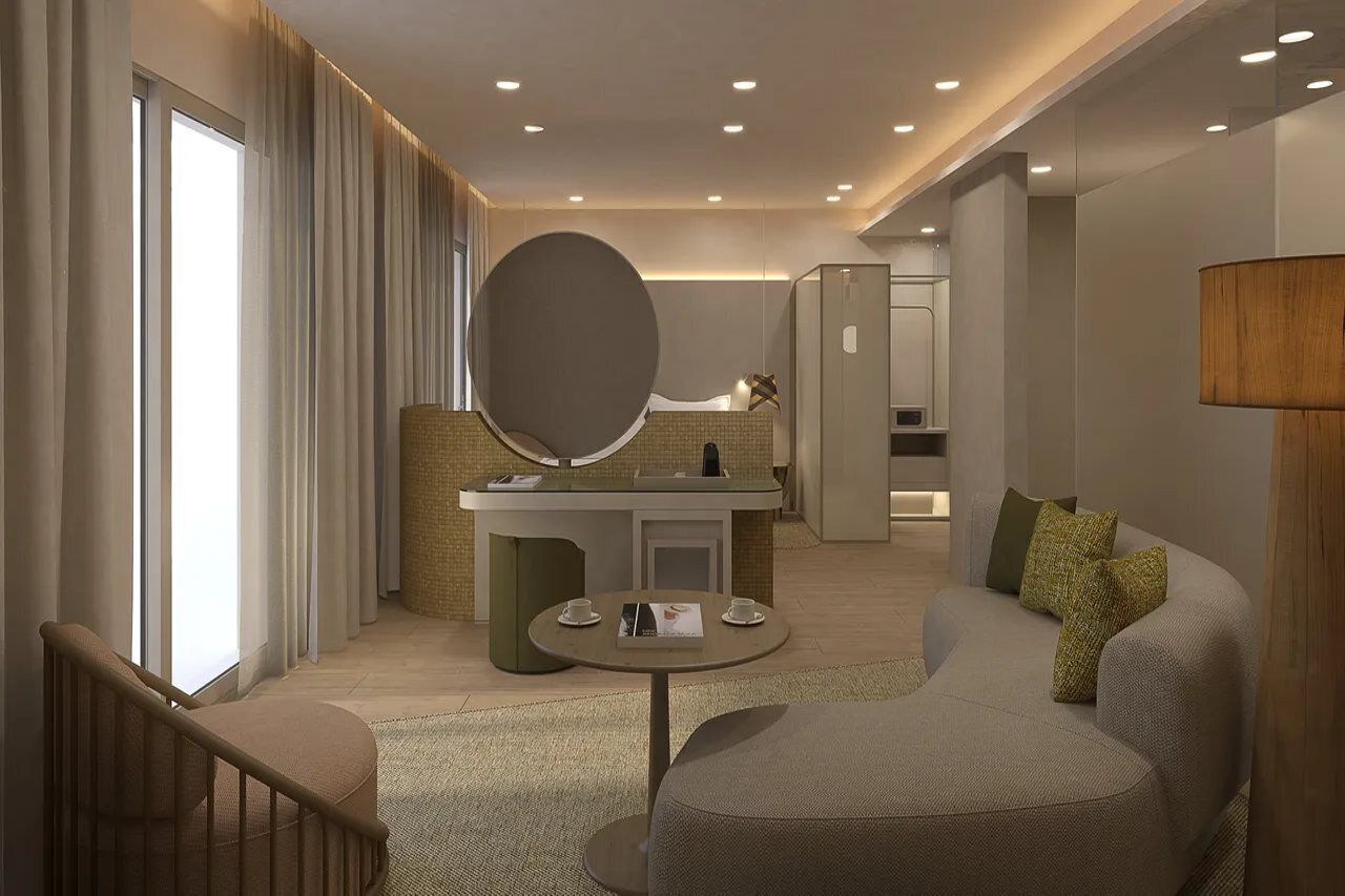 A modern hotel room with a sofa, a round table, a large mirror, and a reception desk.