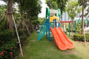 A playground with a slide, climbing structures, and a netted area. - Dusit Grand Condo View by GV (Banglamung)