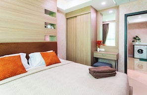 Een hotelkamer met een bed, bureau, spiegel en een wasmachine.