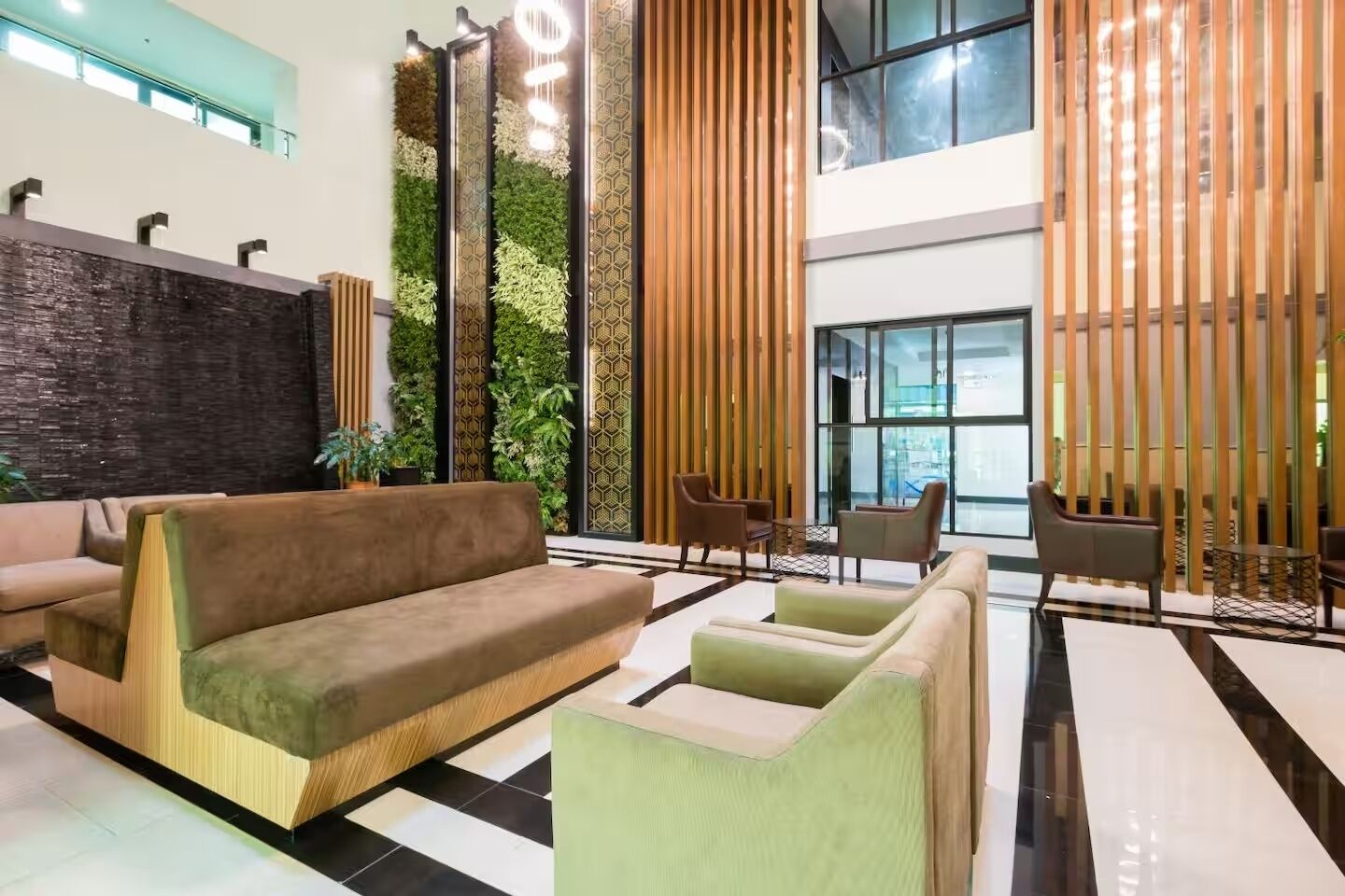 A modern lobby with a sofa, chairs, a decorative wall, and a large window.