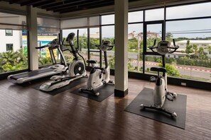 Ein Fitnessraum mit Ergometer, Laufband und großen Fenstern mit Blick nach außen.
