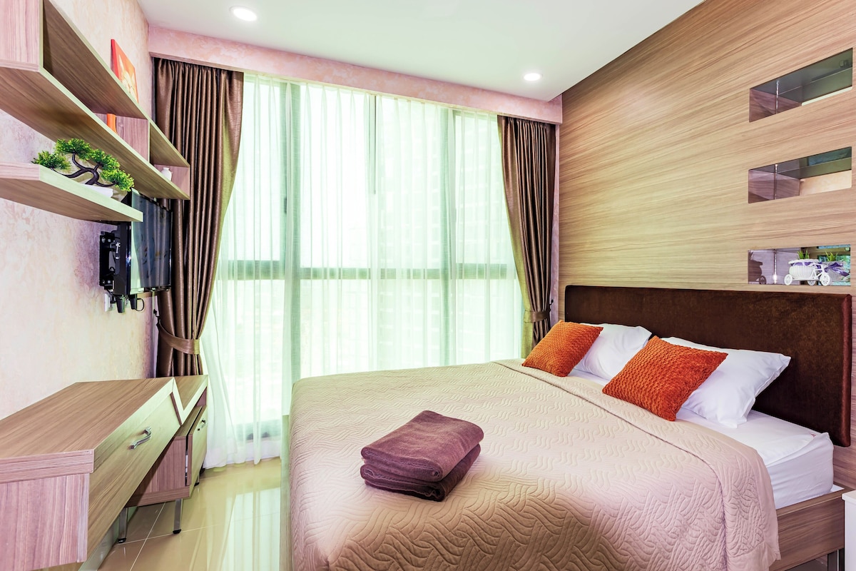 A modern hotel room with a bed, a desk, and a large window with curtains.