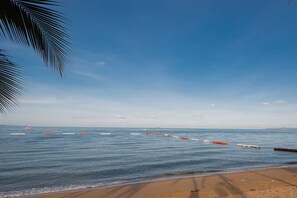 A beach with calm water, a clear sky, and a row of floating barriers. - Dusit Grand Condo View by GV (Banglamung)