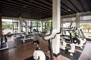 A gym with various exercise equipment, large windows, and a modern design. - Dusit Grand Condo View by GV (Banglamung)