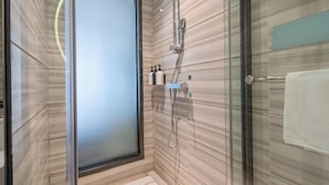 A modern bathroom with a glass shower enclosure, a towel rack, and a marble-tiled wall. - Xana Lite Hotel (Guangzhou)
