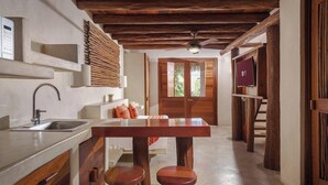 A kitchen with a wooden table and stools, a built-in oven, and a sink. - Hotel El Pueblito (Isla Holbox)