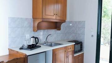 Eine kleine Küche mit Holzausstattung, Geschirrspüler, Mikrowelle und Kaffeemaschine.