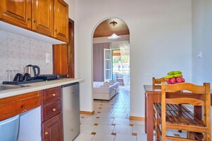 Una cocina con armarios de madera, un lavamanos y una zona de comedor con mesa y sillas.