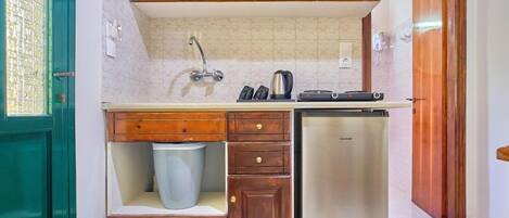 A compact kitchen with wooden cabinets, a stainless steel refrigerator, and a built-in sink.