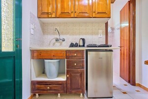 Cocina compacta con armarios de madera, un refrigerador de acero inoxidable y un lavamanos integrado.