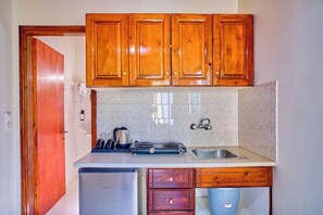 A compact kitchen with wooden cabinets, a built-in stove, and a sink.
