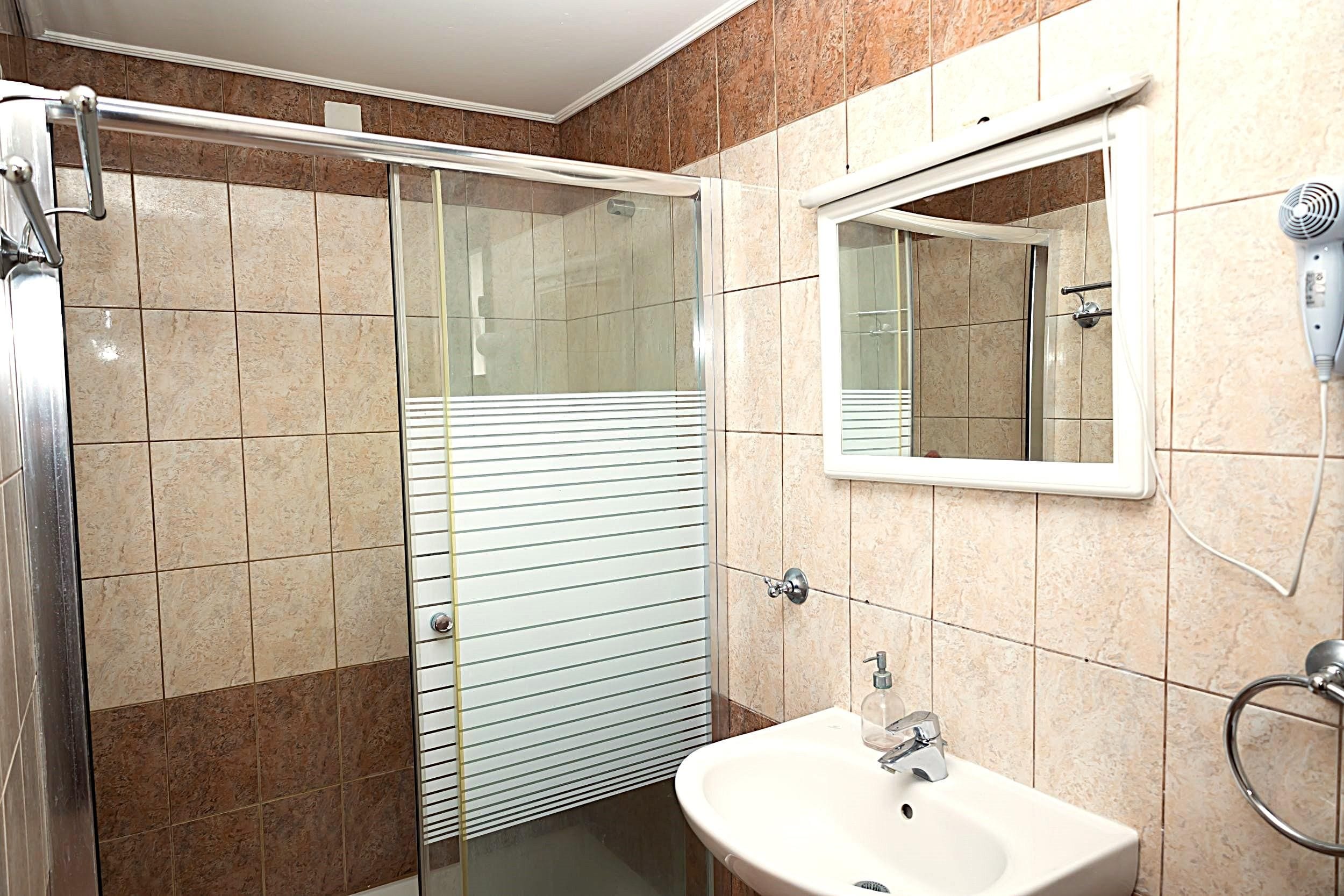 A bathroom with a glass-enclosed shower, a sink with a mirror above it, and a towel rack.