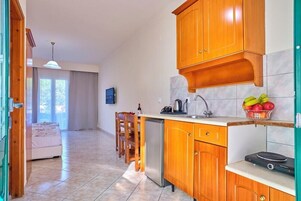 A kitchen with wooden cabinets, a sink, and a countertop with fruits.
