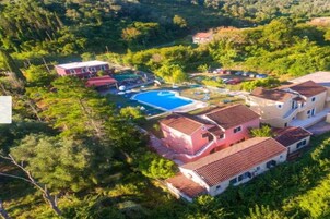 A residential area with a swimming pool, multiple houses, and lush greenery.