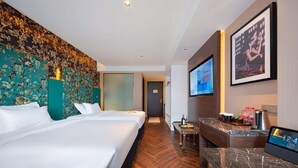 Ein Hotelzimmer mit einem großen Bett, einem Schreibtisch, einem Fernseher und einer Wanduhr.