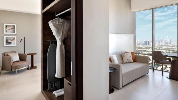 A modern living room with a large window, a sofa, a coffee table, and a view of a cityscape.