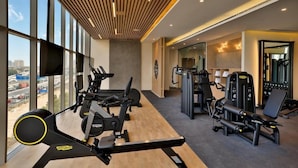 A gym with cardio machines, free weights, and a mirror.