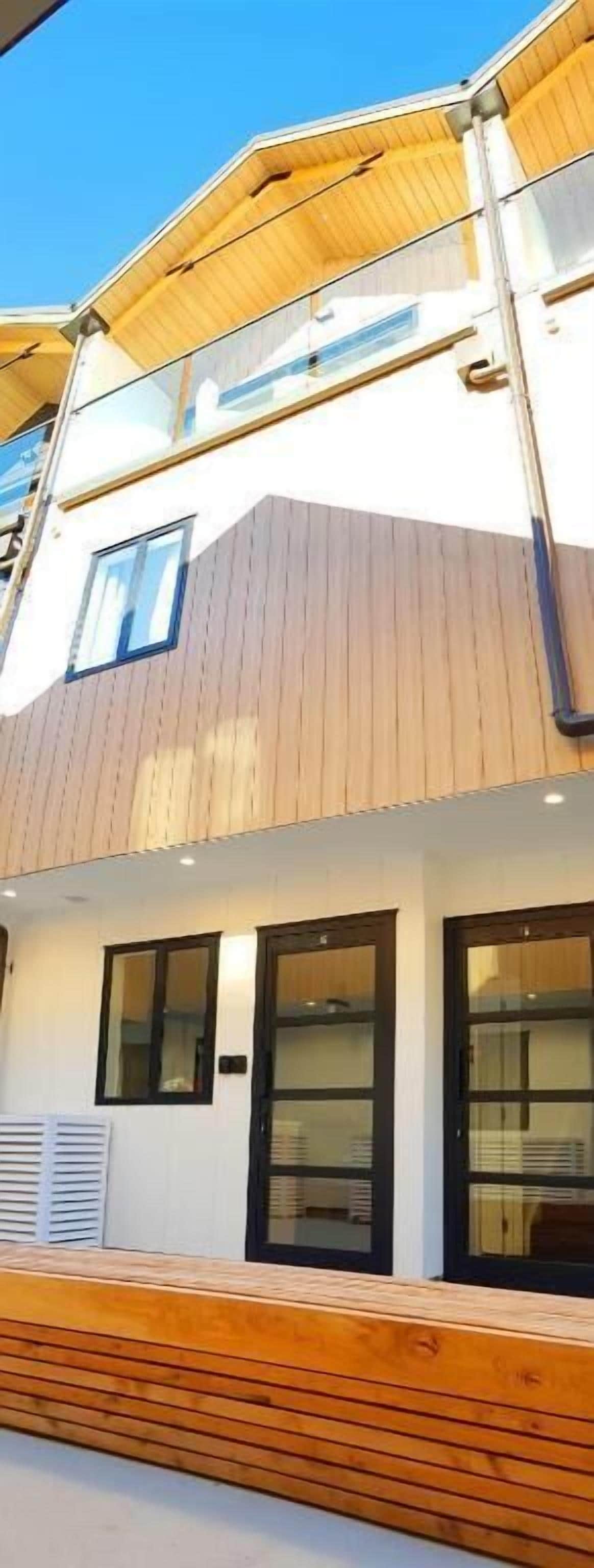 A modern building with a wooden exterior, large windows, and a flat roof.