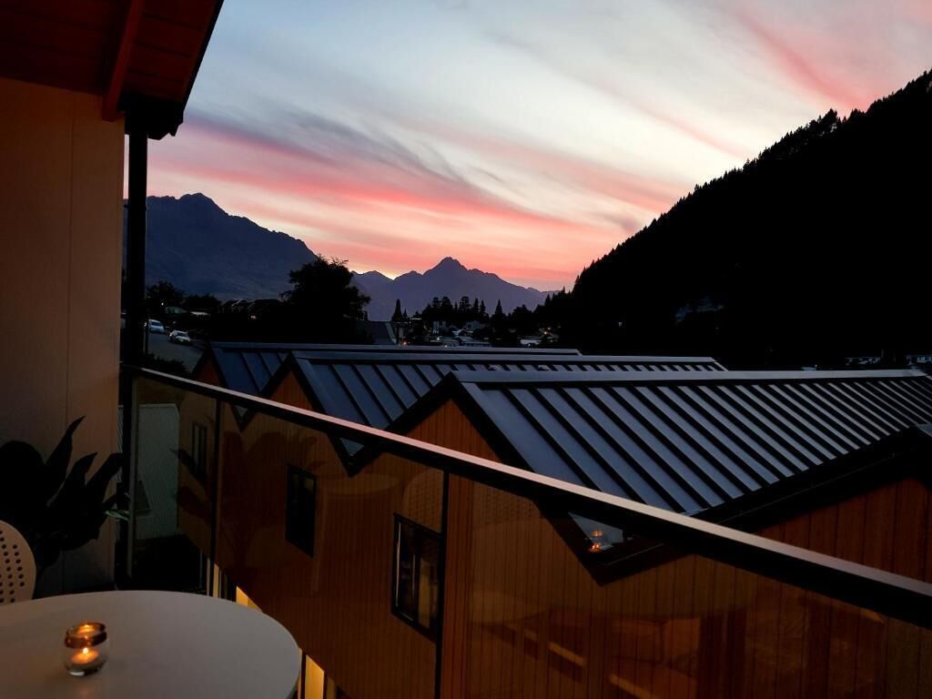 A balcony with a view of mountains and a sunset.