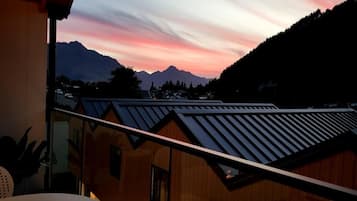 A balcony with a view of mountains and a sunset.