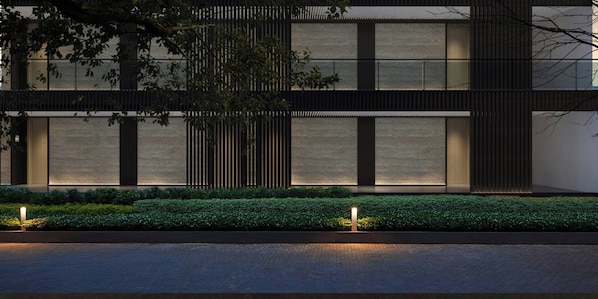 Un edificio moderno con techo plano, ventanas amplias y un seto bien cuidado al frente.