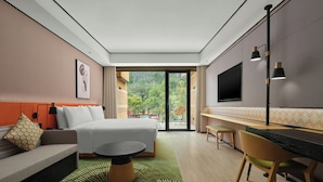 Ein modernes Hotelzimmer mit Bett, Sofa, Schreibtisch und einem großen Fernseher.