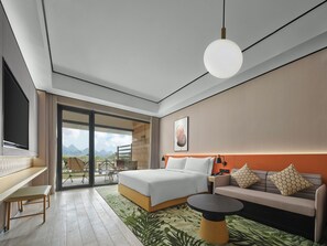 Habitació d'hotel moderna amb llit, sofà i taula petita. Una finestra gran ofereix vistes a l'exterior.