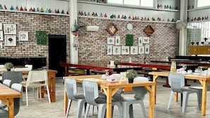 A dining area with brick walls, wooden tables, and grey chairs. - Saga Village Hotel and Resort Bintan (Bintan)