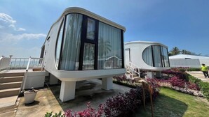 Two modern, curved-room structures with large windows, a concrete base, and a small garden area with plants. - Saga Village Hotel and Resort Bintan (Bintan)
