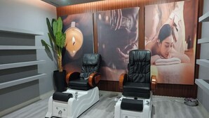A room with two massage chairs, a potted plant, and wall-mounted artwork. - Al Mada Arabia Hotel (Jizan)