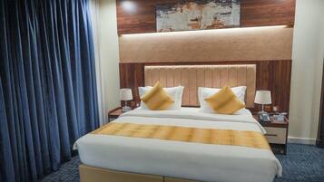 A hotel room with a large bed, two bedside tables, a headboard, and a wall-mounted artwork.